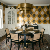 Patterned Guildhall Linen wallpaper with dark green and white floral damask designs, styled in a dining room.
