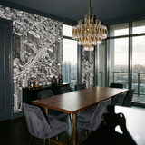 Bayou City Blueprint Wallpaper with city pattern and tall buildings, near dark wood dining table and gold chandelier.