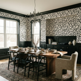 Black and white wallpaper with swirling line pattern by Inkline, covering dining room walls above dark wood wainscoting.
