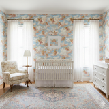 Pastel blue wallpaper with cherub pattern, by Allegro, decorating a nursery room with white furniture.