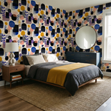 Patterned wallpaper with blue, yellow, pink, and black shapes, styled in a bedroom.
