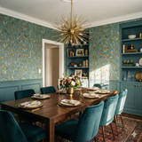 Floral stem wallpaper with gold accents, patterned on an aqua-teal wall behind a dining room setting.