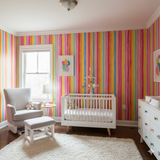 Colorful striped Prism Parade Wallpaper, from York Wallcoverings, in a baby room with bright stripes.
