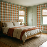 Fieldstone Picnic Check Wallpaper with a pattern of intersecting orange and sage green squares on a bedroom wall.
