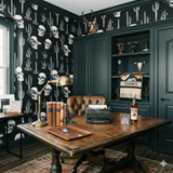 Desert Relic Nocturne wallpaper with skull and cactus pattern, on a dark moody wall.
