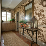 Citron Etch Wallpaper with leaf pattern, in brown tones on beige, covering a traditionally styled hallway.

