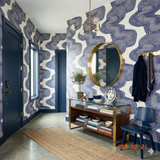 Cobalt drift wallpaper by Livette's Wallpaper with a swirling blue pattern on an off-white background, as seen in a styled entryway.
