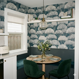 Patterned wallpaper with tree canopy design, with books and decorative objects on a shelf.