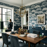 Blue tree wallpaper with white canopy pattern, from Zephyr, in a dining room setting.
