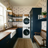 Coquette wallpaper with bow pattern on the wall, styled in a laundry room with blue cabinets and open shelving.