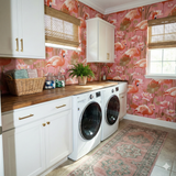 Patterned wallpaper with flamingos by York Wallcoverings over a laundry room setup with white cabinets and gold hardware.