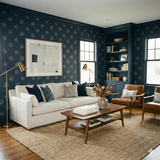 Navy blue wallpaper by Wallshoppe with a starburst pattern, decorating a living room with sofa and brown chairs.