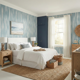 Blue and white linen bands wallpaper with vertical stripes, from Brewster, in a bedroom setting.
