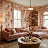 Patterned wallpaper with woman illustrations, styled with a brown sectional sofa and round wood coffee table.
