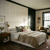 Champagne stipple wallpaper with gold dot pattern on the wall behind a bed.