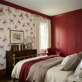 Keepsake Loop Wallpaper with red bow pattern on a light background, shown in a styled bedroom setting.