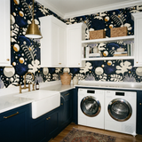 Floral pattern wallpaper with dark blue background, decorated with white cabinets and white front loading washing machines.