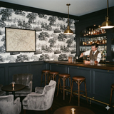 Queen’s Crossing Carriageway Wallpaper with a toile pattern featuring buildings and trolleys.
