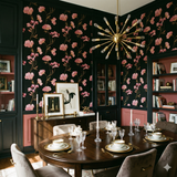 Black floral wallpaper with pink flowers from Atelier Nocturne, covering a dining room.
