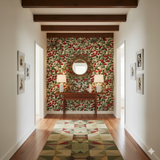 Cranberry Crawl wallpaper with a leaf and berry pattern, covering a wall with lamps and a mirror on display.
