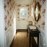 Bridle Rue wallpaper with a pattern of hats, styled in a hallway above white wainscoting.