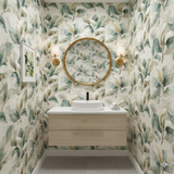 Eucalyptus Vale Wallpaper with a leaf pattern filling the wall behind a round mirror and sink.