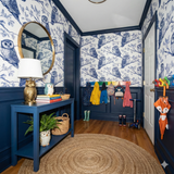 Nocturne Branchkeepers Wallpaper with owl pattern over dark blue wainscotting, with round mirror and other hallway decorations.