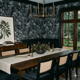 Botanique wallpaper in a black and white floral pattern, Havenshade Botanique Wallpaper, accenting a dining room wall with dark trim.