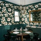 Floral wallpaper with camellia pattern, from Wallshoppe, in a dark green botanical style with white blossoms.
