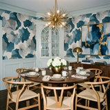 Blue and white botanical wallpaper with abstract leaves, by York Wallcoverings, in a styled dining room setting.