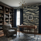 Blue and white cloud patterned wallpaper, with navy drapes, chandelier, desk, chair, and full bookcase.