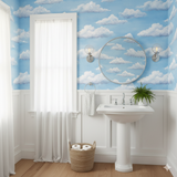 Blue sky and cloud pattern wallpaper featuring wispy white clouds, with matching round mirror reflecting the same pattern.
