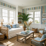 Drifted Strata Wallpaper with vertical stripes of blue, teal, and tan, installed above windows in a well-lit living room.
