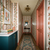 Floral dahlia regency wallpaper with stripe pattern, from York Wallcoverings, in a hallway with teal rug and salmon colored door.