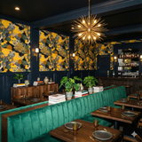 Leopard print wallpaper with yellow background by [Vendor] featuring green accents in a dark-walled restaurant.