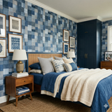Indigo patchwork atelier wallpaper with squares, in a bedroom setting, with framed art on the walls.
