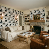 Patterned wallpaper with dog silhouettes, from Shadowmere Bay, covering walls and fireplace in cozy living room setting.

