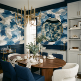 Bluewash terrain wallpaper with blue, grey, and white abstract patterns, complemented by a round gold mirror.
