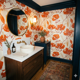 Patterned wallpaper with orange floral design on cream backing, tiling a bathroom with dark blue trim.
