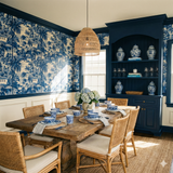 Blue and white Mariner’s Quiet Wallpaper with a tropical motif, and visible palm trees and houses.
