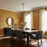 Gold spotted wallpaper with black polka dots, by Savara Pelt, in a dining room setting.