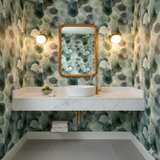 Leafy patterned Silverwood Wallpaper with green and gray hues, covering a powder room with a vessel sink and gold accents.