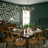 Green leaf-patterned wallpaper, Hearthwood Canopy Wallpaper, with a traditional style, set above a wainscot.
