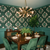 Green and white floral wallpaper with a damask pattern, covering the walls of a vintage style dining room.