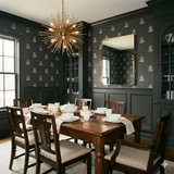 Charcoal wallpaper with bell pattern, from Harborsong, in a dining room setting with dark wood furniture.
