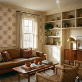 Copper rosette field wallpaper with floral pattern, against a neutral wall in a living room.