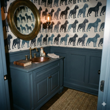 Patterned wallpaper with Cane Corso dogs, above dark blue wainscoting and vanity.
