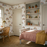 Sunset Reverie Wallpaper with rainbow pattern on a white wall, complementing a bedroom with wooden chair and bed.