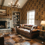 Kodiak Dust wallpaper with cowboy boot pattern, styled in a rustic room with stone fireplace.
