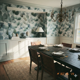 Patterned wallpaper with a leaf design by Aspenveil, adorning an interior room above white painted panelling.